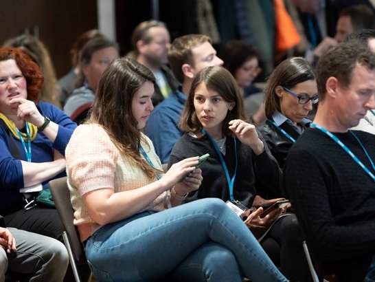 ÖAD Fachtagung Erasmus + im Hotel Flemings Wien Viele Menschen in Plenum sitzend, zwei Frauen sind im Gespräch miteinander